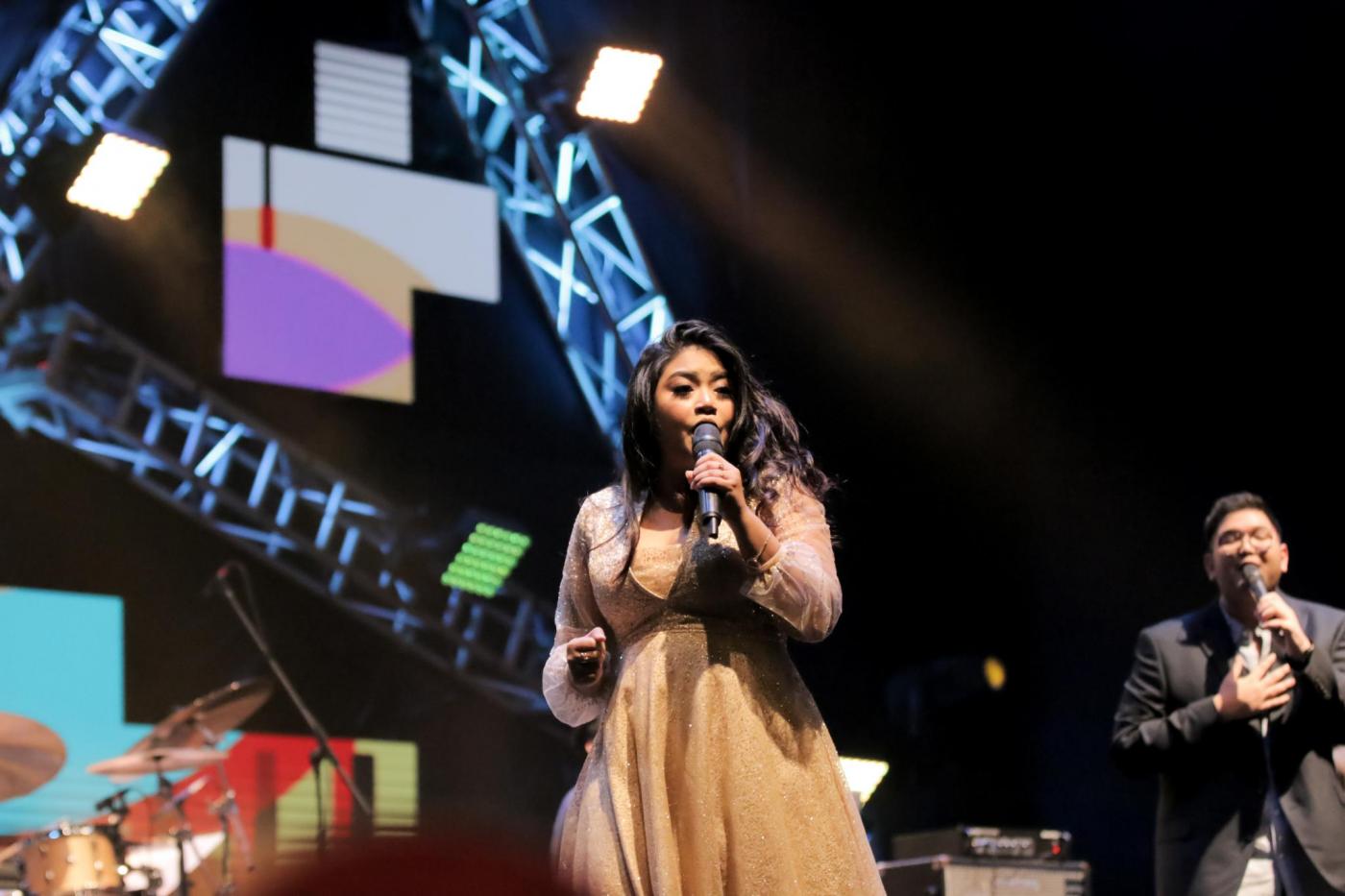 Windy Dreikids menggunakan gaun berwana krem sedang bernyanyi